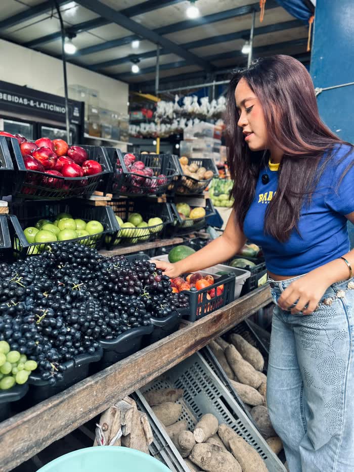 Júlia escolhendo frutas em um mercado, conteúdo de campanha