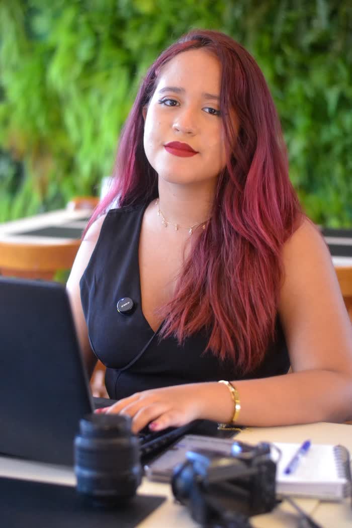 Júlia olhando para a câmera enquanto trabalha no laptop
